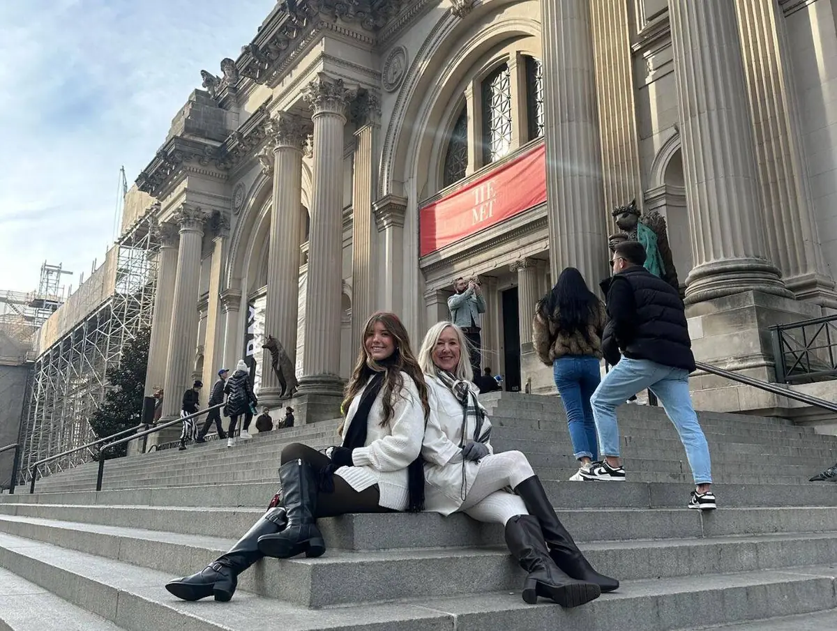Mutter und Tochter sitzen bei einem winterlichen Besuch mit Gossip Girl Tours auf den Met Steps
