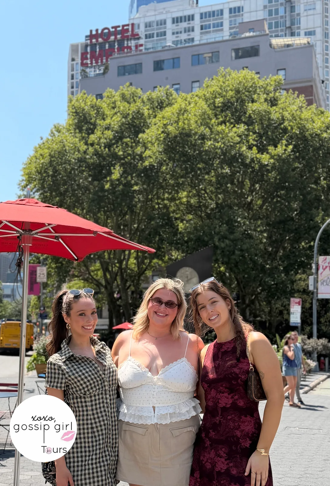 Three Gossip Girl Tours guests posing beneath the Hotel Empire sign in New York City