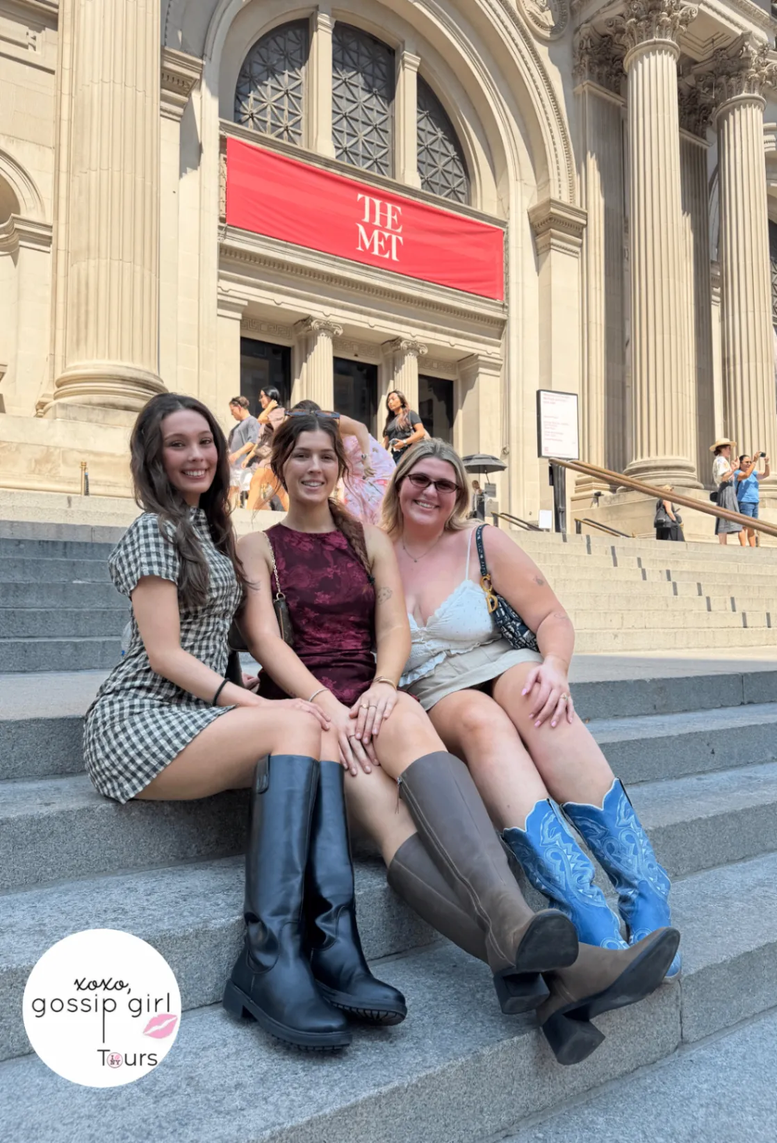 Three friends sitting on the Met Steps under the red banner on a Gossip Girl tour of the Upper East Side